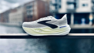 Brooks Glycerin Max ( Running Shoes ) Brooks running shoe with thick cushioned sole and mesh upper, placed on a railing with blurred cityscape background